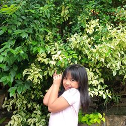 Portrait of young asian girl standing by plants