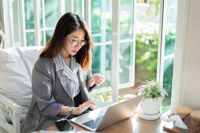 Young woman using phone while sitting on table