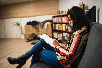 Smiling young woman using digital tablet while sitting at office