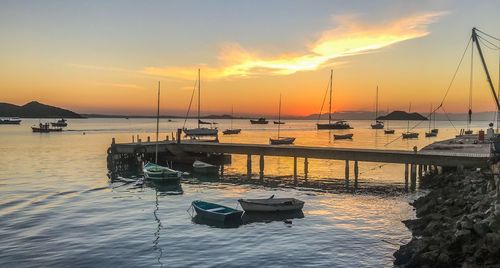 Boats moored in sea at sunset