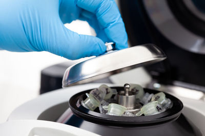 Closeup of a scientist closing an small table centrifuge filled with tubes.