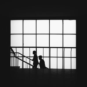 Silhouette people standing in window