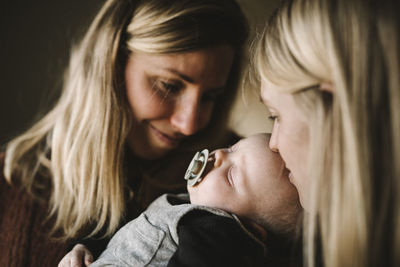 Smiling mothers holding sleeping newborn baby