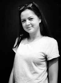 Portrait of smiling young woman against black background