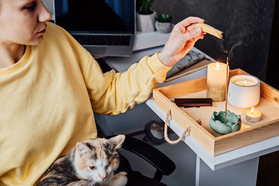 Mental health and work. work life balance. young woman with cat lighting candles, relaxing and