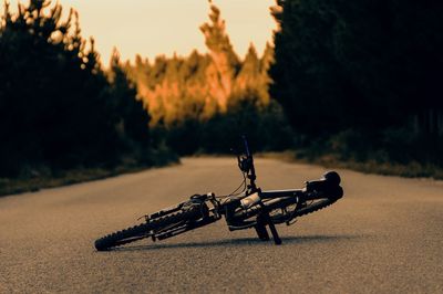 Close-up of bicycle on land against sky at sunset