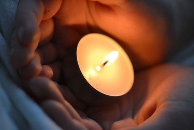 Close-up of hand holding burning candle