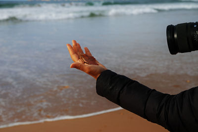 Midsection of person photographing sea