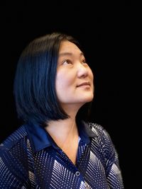 Woman looking away against black background