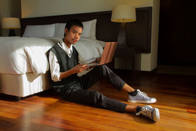 Portrait of young man using laptop while sitting on the floor 