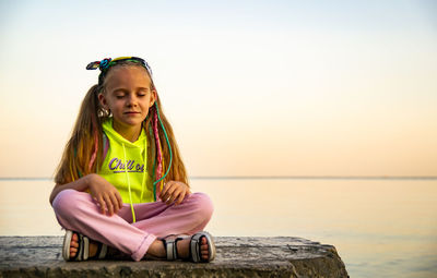 Portrait of happy girl sitting against sky