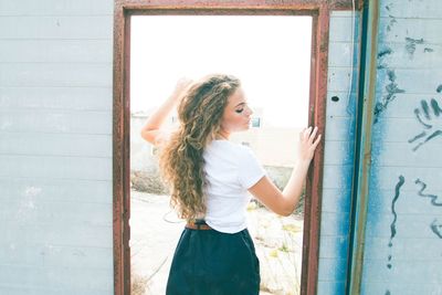 Beautiful young woman standing against wall