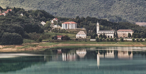 House by lake and buildings against mountain