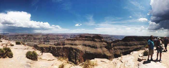 Rear view of people on rock formation against sky