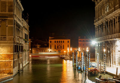 Canal amidst buildings in city at night