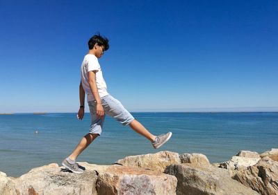 Side view of man walking on rocks against horizon