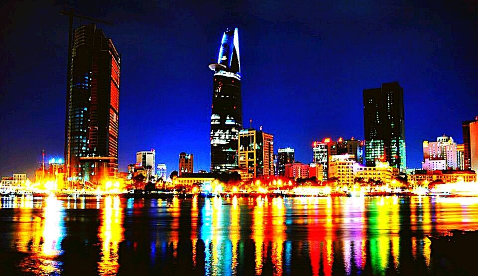 illuminated, night, building exterior, architecture, built structure, city, water, waterfront, reflection, skyscraper, tall - high, tower, modern, river, cityscape, office building, urban skyline, city life, clear sky, sky