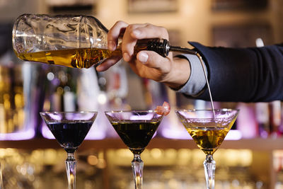 Cropped hand of bartender preparing cocktail in bar