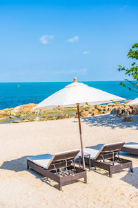 Deck chairs and parasols on beach against sky