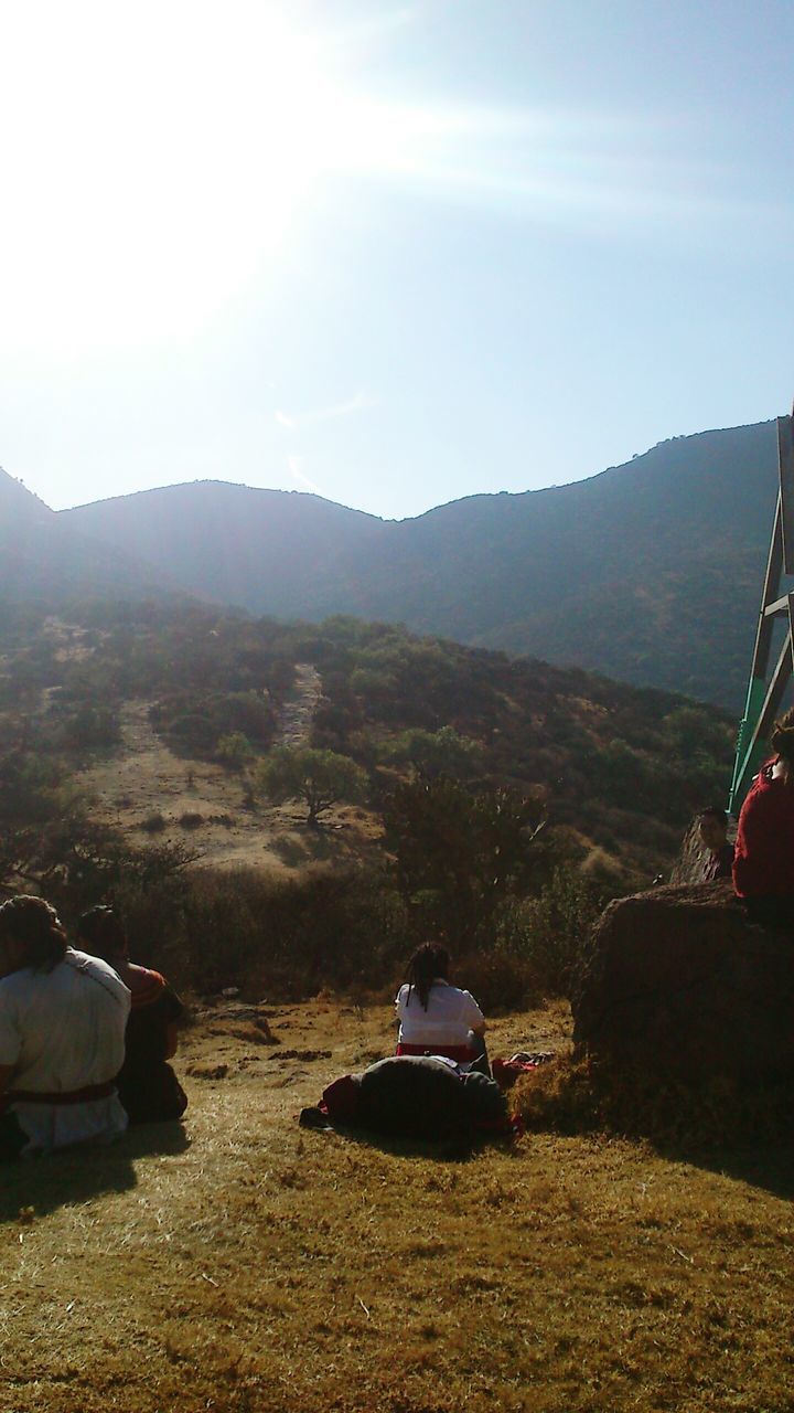 mountain, land vehicle, nature, beauty in nature, sunlight, outdoors, sky, mountain range, leisure activity, real people, day, landscape, tree