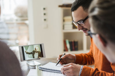 Colleagues discussing in office with video film on digital tablet in background