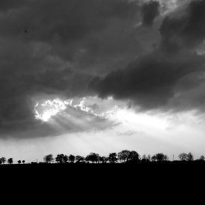 Silhouette landscape against cloudy sky