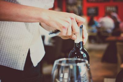 Midsection of man opening wine bottle