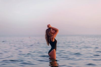 Young woman standing in sea against clear sky