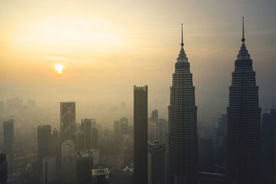 Buildings in city against sky during sunset