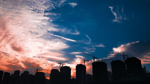 Low angle view of silhouette buildings against sky at sunset