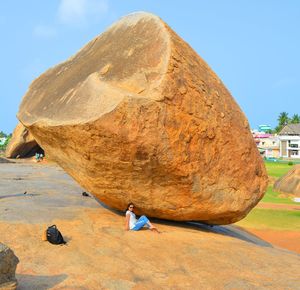 Side view of woman on rock formations against sky