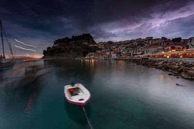 Boats moored in river by cityscape against sky