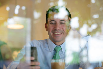 Portrait of smiling young man using smart phone outdoors