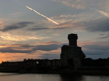 Scenic view of river by building against sky during sunset