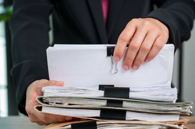 Midsection of man holding paper stack on table