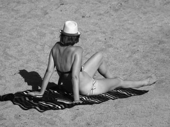 High angle view of woman in bikini sunbathing at beach on sunny day