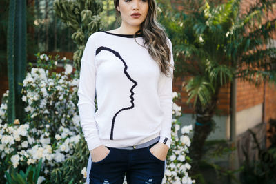 Beautiful young woman standing against plants