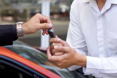 Midsection of man receiving car key