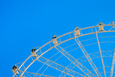 Low angle view of ferris wheel against clear blue sky