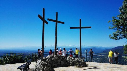 People standing by sea against clear blue sky