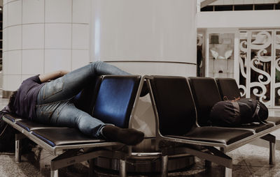 Man sleeping on chairs at waiting area