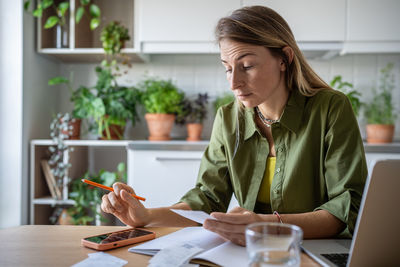 Surprized female seeing high expenses in bills, receipts, understands of having financial difficulty