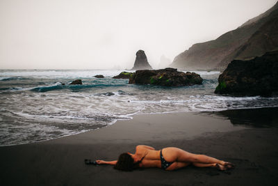 People lying on beach against clear sky