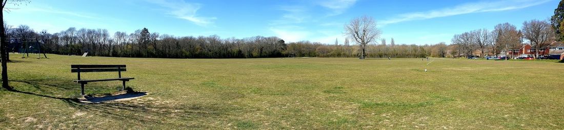 Park bench on field against sky