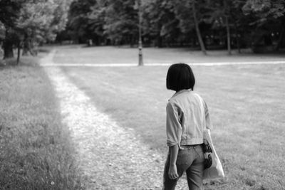 Rear view of boy walking on grassland