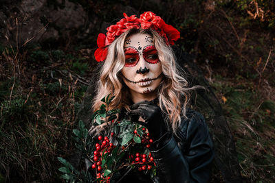 Closeup portrait of calavera catrina. young woman with sugar skull makeup and red flowers. dia 