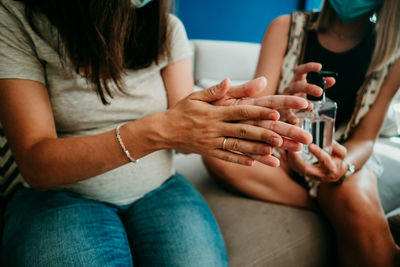 Midsection of women using hand sanitizer at home