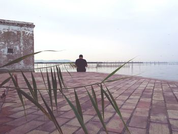 Rear view of silhouette man overlooking calm sea