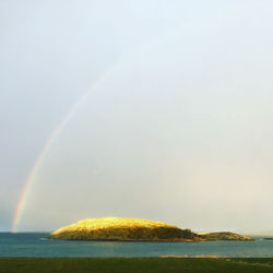 Scenic view of rainbow over sea against sky