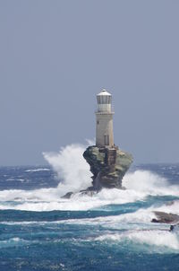 Lighthouse by sea against clear sky